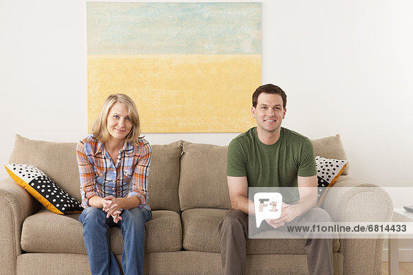 Smiling mid adult couple sitting on sofa