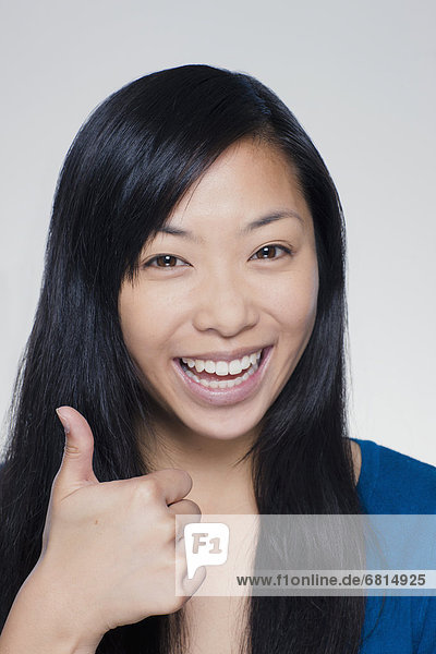 Studio portrait of young woman showing thumbs up sign