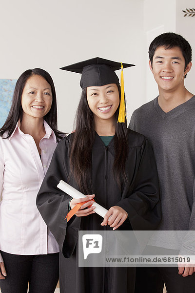 Portrait of young woman in graduation gown with mother and brother