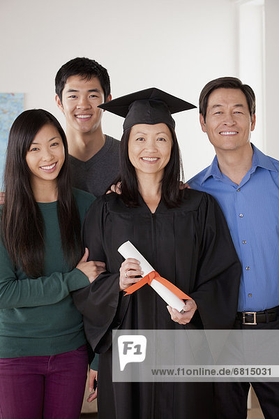 Portrait of mature woman in graduation gown with family