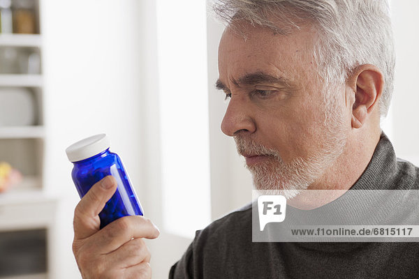 Senior men reading label on medicine bottle