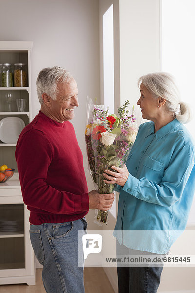 Senior man giving flower to woman
