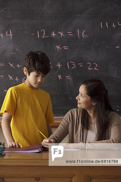 Schoolboy (12-13) and teacher with blackboard in background