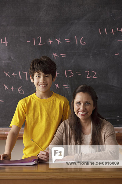 Portrait of schoolboy (12-13) and teacher with blackboard in background