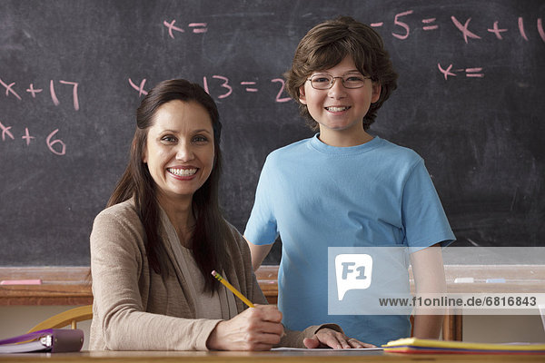 Portrait of schoolboy (10-11) and teacher with blackboard in background