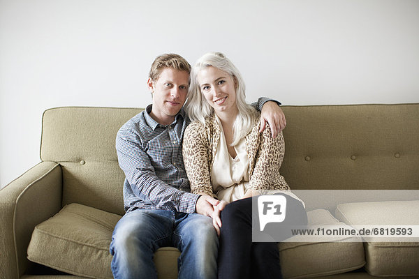 Portrait of happy young couple sitting on sofa