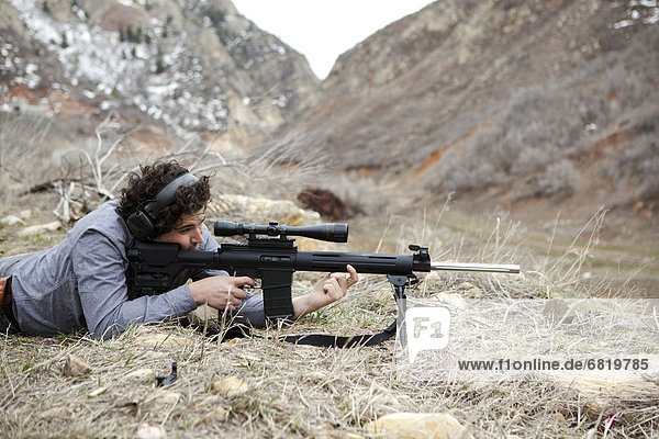 Man lying on front with weapon