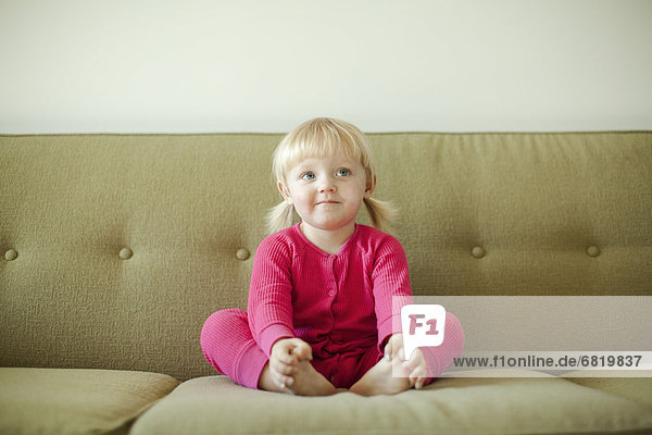 Portrait of baby girl (18-23 months) sitting on sofa