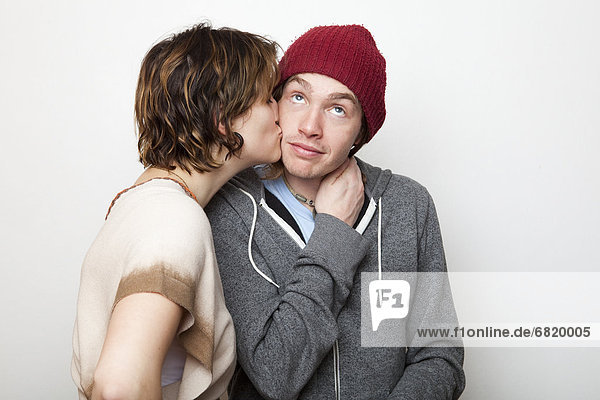 Studio Shot of young woman kissing young man