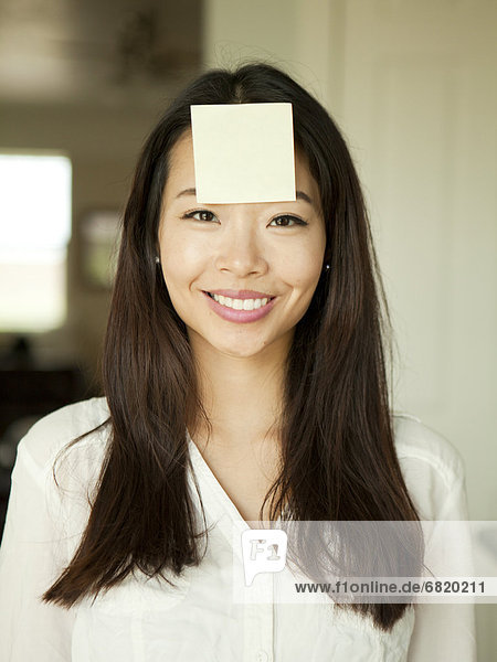 Portrait of young woman with adhesive note stuck to her forehead