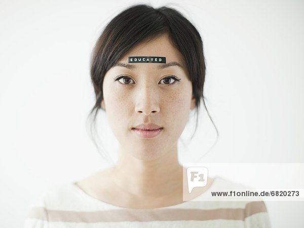 Portrait of young woman with word 'educated' on forehead  studio shot