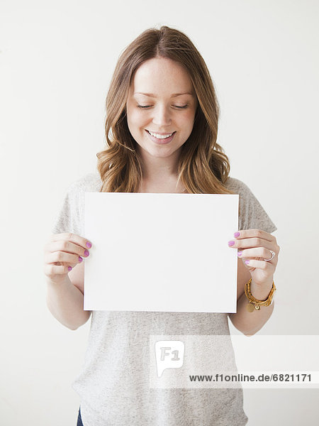 Portrait of cheerful young woman holding blank card