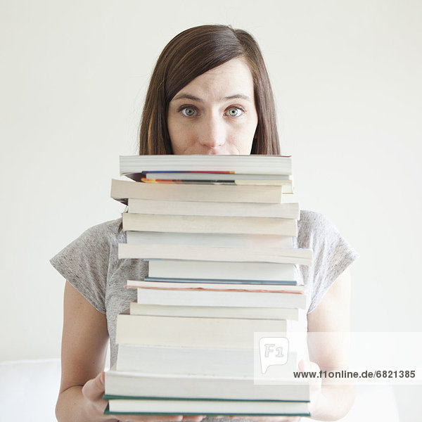 Young woman holding stack of books