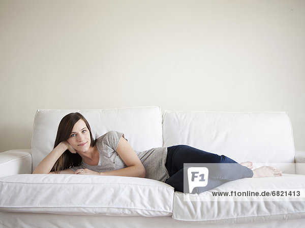 Happy young woman reclining on bed