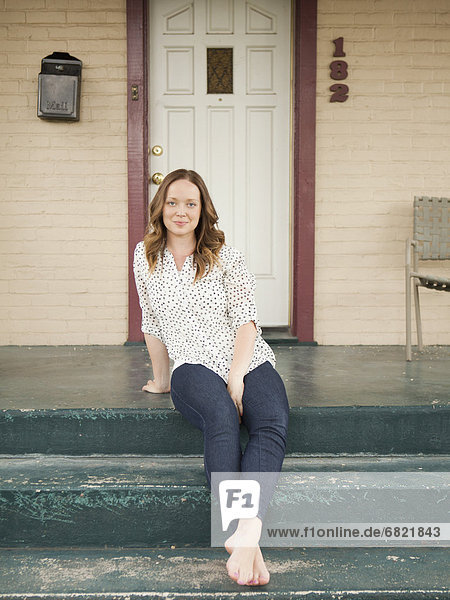 Portrait of happy young woman standing on porch