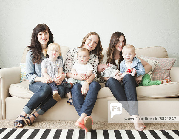 Three young mothers with toddler girl (2-3) and tow baby boys (2-5 months  6-11 months) posing for portrait