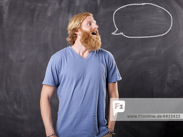 Man in front of blackboard with drawing depicting speech bubble
