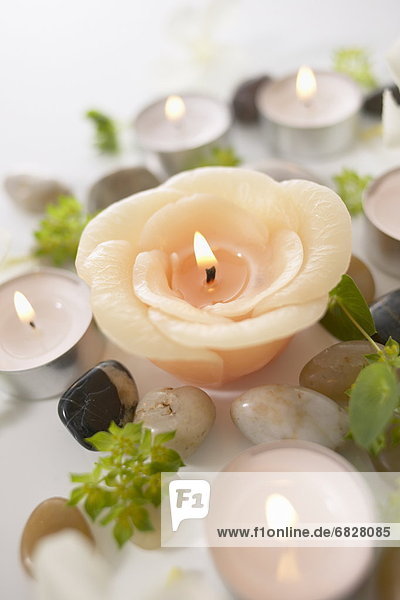 Burning candles and stones  close up  white background
