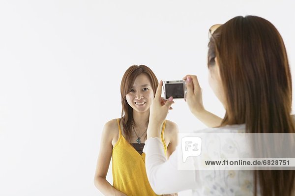 Young woman taking a photograph of her friend