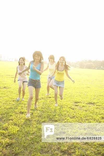 Four friends running in a field