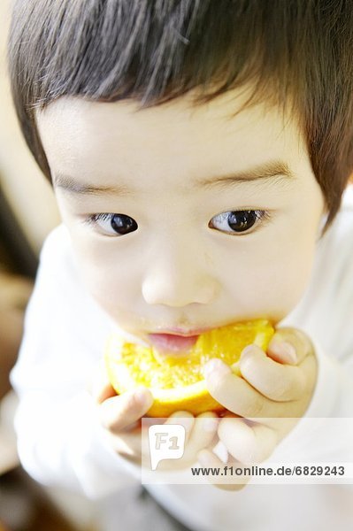 Little boy eating orange slice