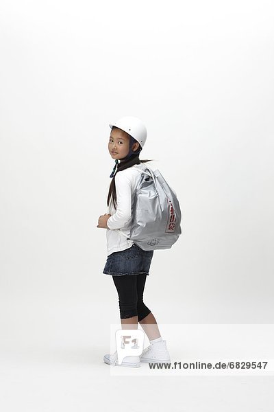 School girl wearing a safety helmet and a disaster prevention pack