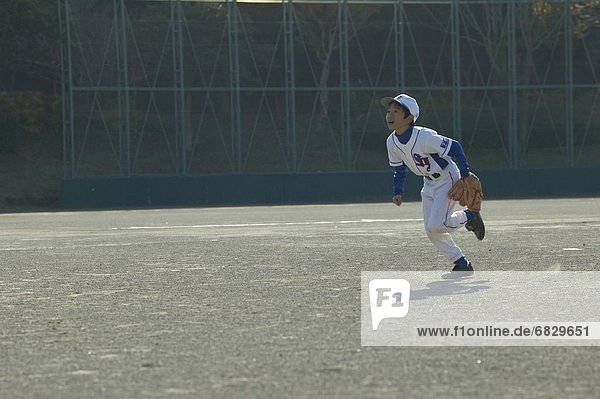 Boy in baseball uniform trying to catch a ball