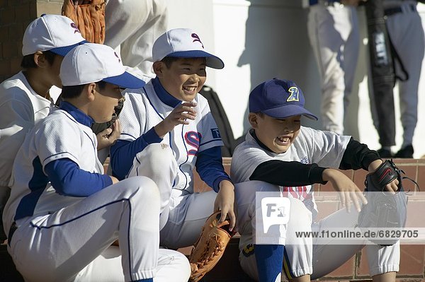 Boys in baseball uniform sitting on stairs  smiling