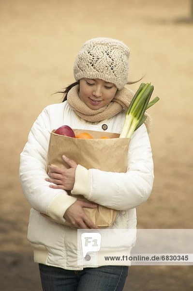 Young woman walking in park  holding shopping bag