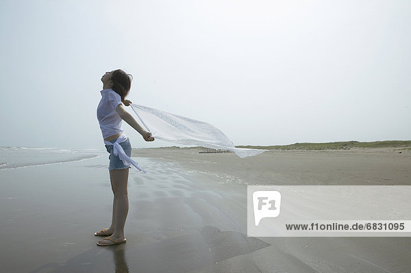 Young woman standing at beach  holding cloth