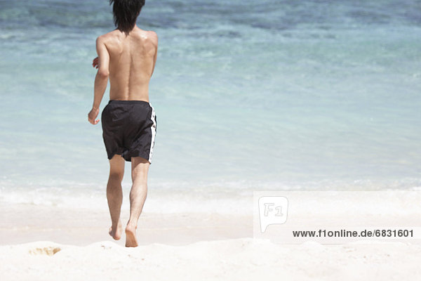 Young man running on beach  Guam USA