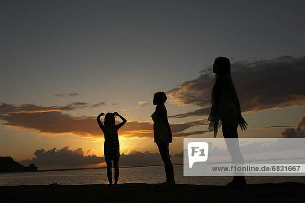 Young women standing on beach at dusk  Guam  USA