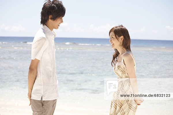 Young couple standing face to face on beach holding gifts  Guam  USA