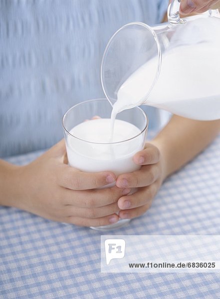 A child's hands holding a glass of milk