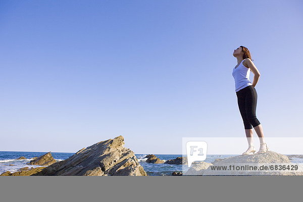 Young woman standing on rock on beach  copy space  Hitachinaka city  Ibaragi prefecture  Japan