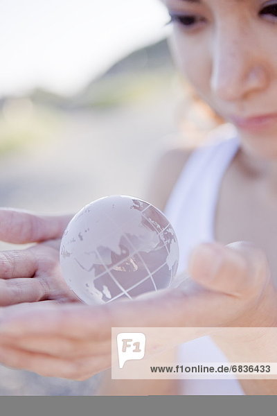 Young woman holding globe in hands  close up