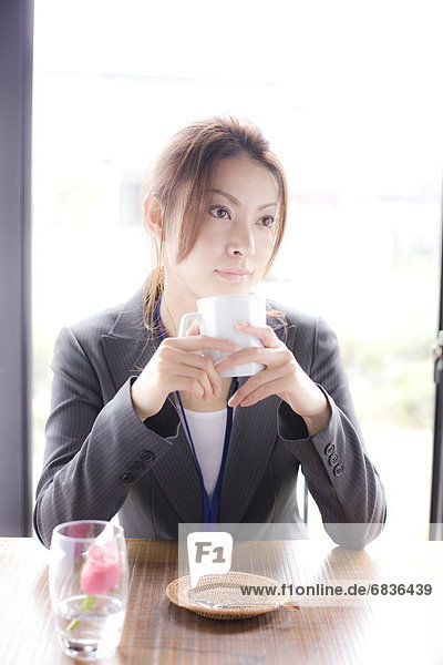 Young businesswoman holding mug in cafe  looking away