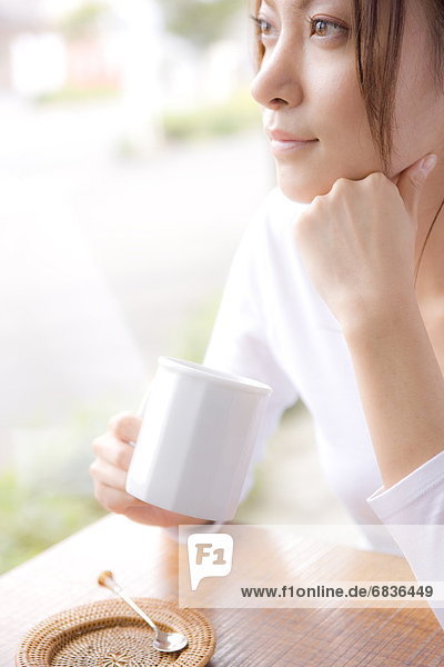 Young woman holding mug in cafe  looking away
