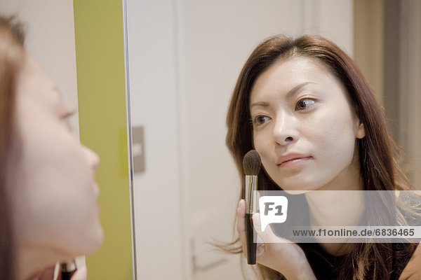 Young Woman Making Up  Looking at Mirror