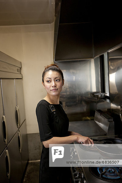 Young Woman Cooking at Kitchen in Restaurant