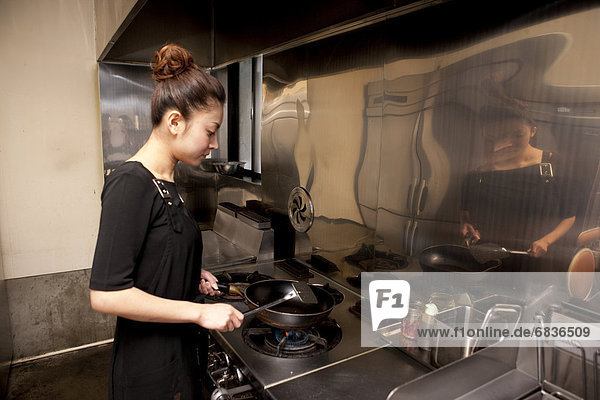 Young Woman Cooking at Kitchen in Restaurant