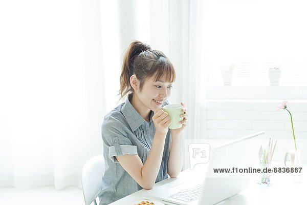 Young woman drinking a coffee and using a laptop