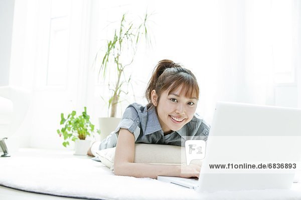 Young woman lying down and using a laptop