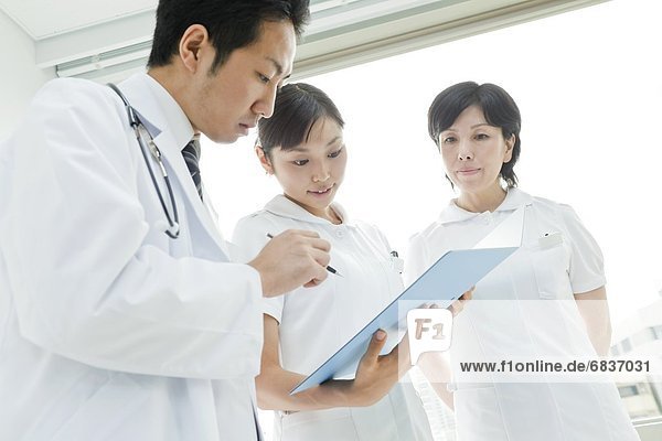 Doctor and nurses looking at clipboard