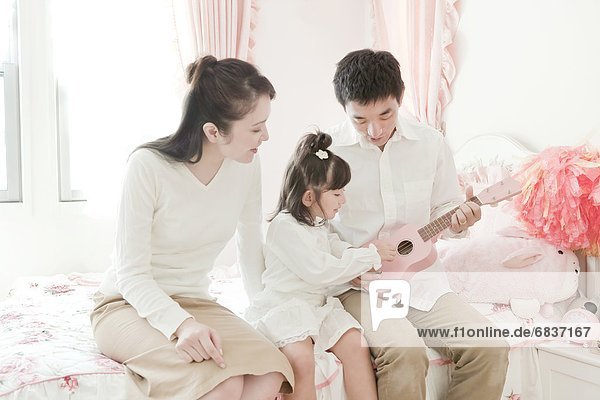 Mother and Father Playing Ukulele with Daughter