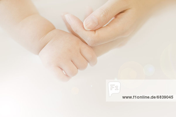 Baby holding woman's finger