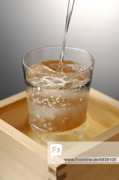 Sake pouring into glass  colored background