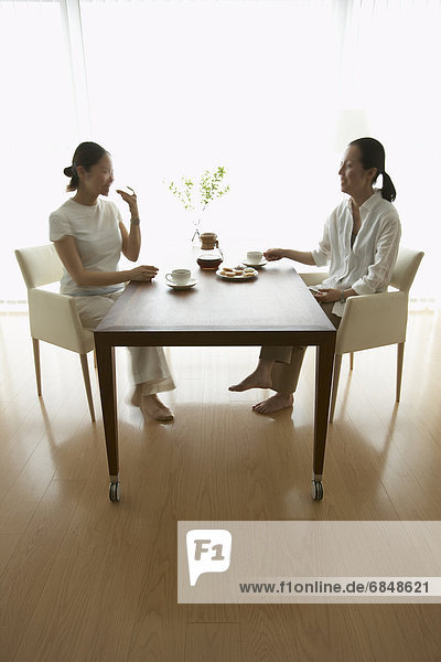 Two women sitting at table  drinking coffee