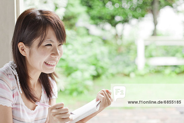 Frau  schreiben  Notizblock  lächeln  jung  Japan
