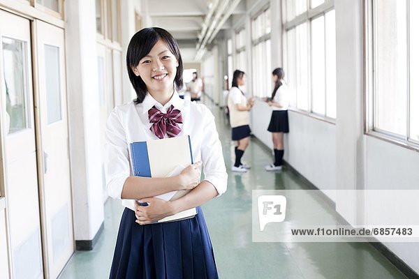 A Japanese Schoolgirl Standing in a School Corridor and Smiling